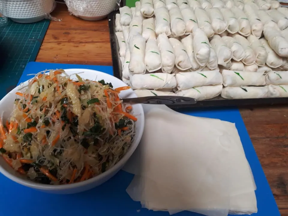 Behind-the-scenes kitchen prep: tray of freshly rolled spring rolls and filling ingredients